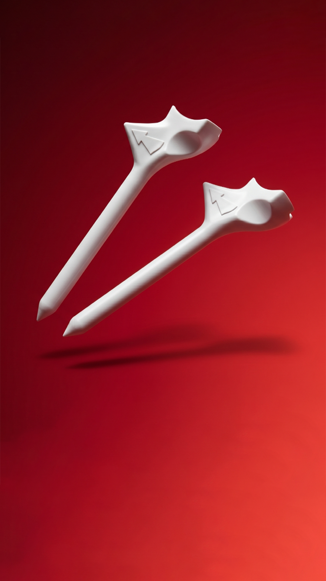 Two FlightPath golf tees, our own brand's product, on a red studio background